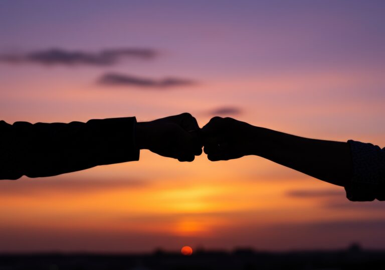 Fist bump silhouette at sunset symbolizes collaboration and success
